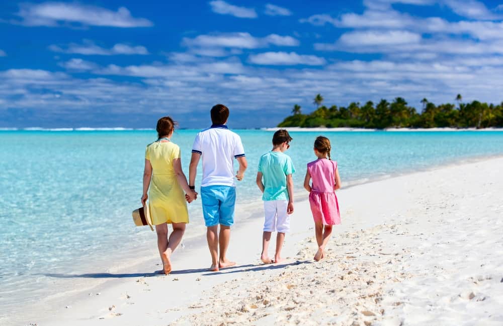 family walking on tropical sunny beach